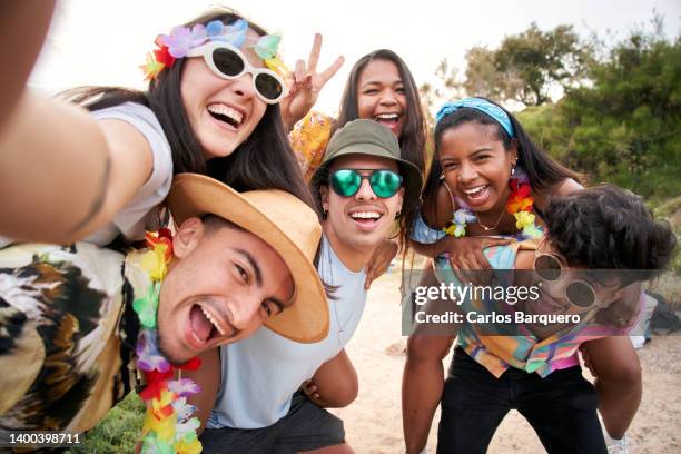 three couples piggybacking while taking a selfie at a beach party. - carnaval evento de celebración fotografías e imágenes de stock