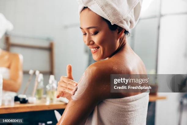mujer poniéndose crema después de una ducha - crema hidratante fotografías e imágenes de stock