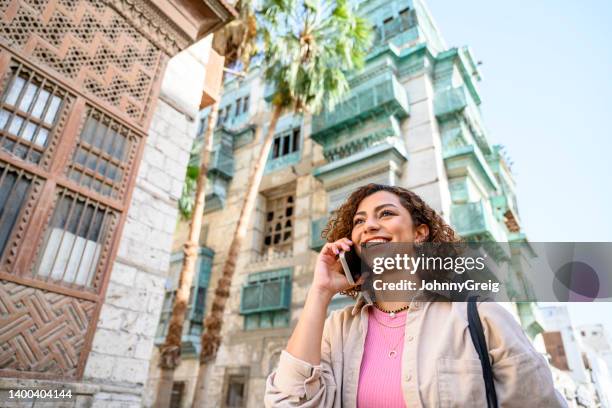 lächelnde junge dschidda-frau mit telefon im freien - portrait frau arabisch frontal stock-fotos und bilder