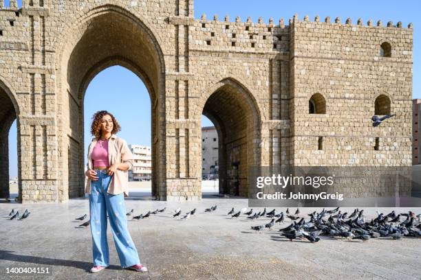 smiling young woman standing at jeddah gateway monument - jiddah stock pictures, royalty-free photos & images