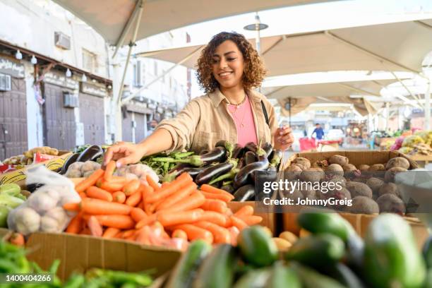 junge dschidda-frau, die auf dem bauernmarkt nach produkten sucht - bazaar stock-fotos und bilder