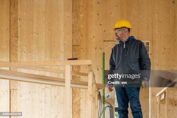 foreman in hardhat standing at house construction site - general maintenance stock pictures, royalty-free photos & images