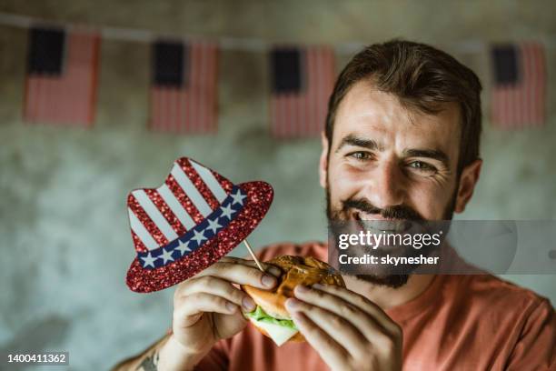 young happy man eating burger on independence day. - burger with flag stock pictures, royalty-free photos & images