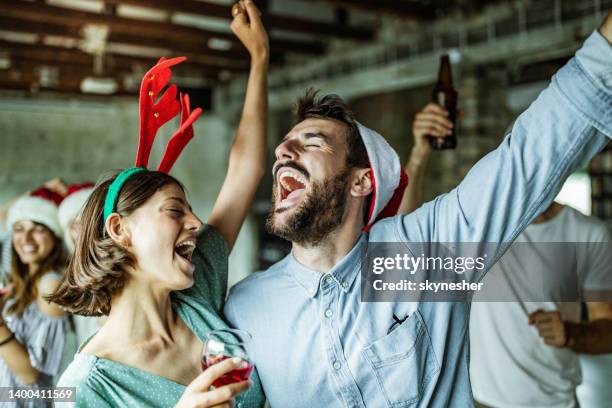 feliz pareja divirtiéndose mientras canta en la fiesta de navidad. - christmas party fotografías e imágenes de stock