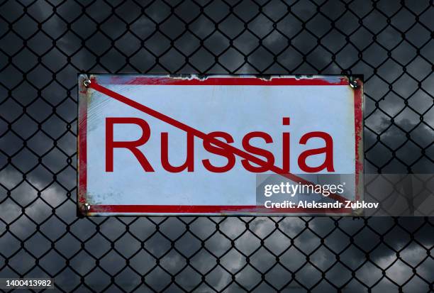 black thickening clouds and a crossed-out inscription "russia", against a background of barbed wire. sanctions against the country. problems, economic and financial crisis due to military actions and offenses. - russia fotografías e imágenes de stock