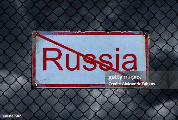 black thickening clouds and a crossed-out inscription "russia", against a background of barbed wire. sanctions against the country. problems, economic and financial crisis due to military actions and offenses. - sanctions foto e immagini stock