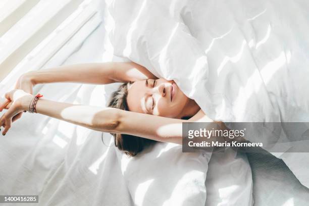 woman sleeping under duvet at the sunny morning, top view. - vrouwelijk stockfoto's en -beelden
