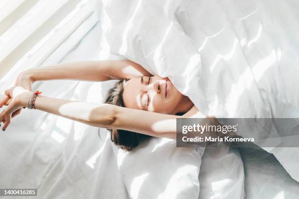 woman sleeping under duvet at the sunny morning, top view. - happy morning stock pictures, royalty-free photos & images