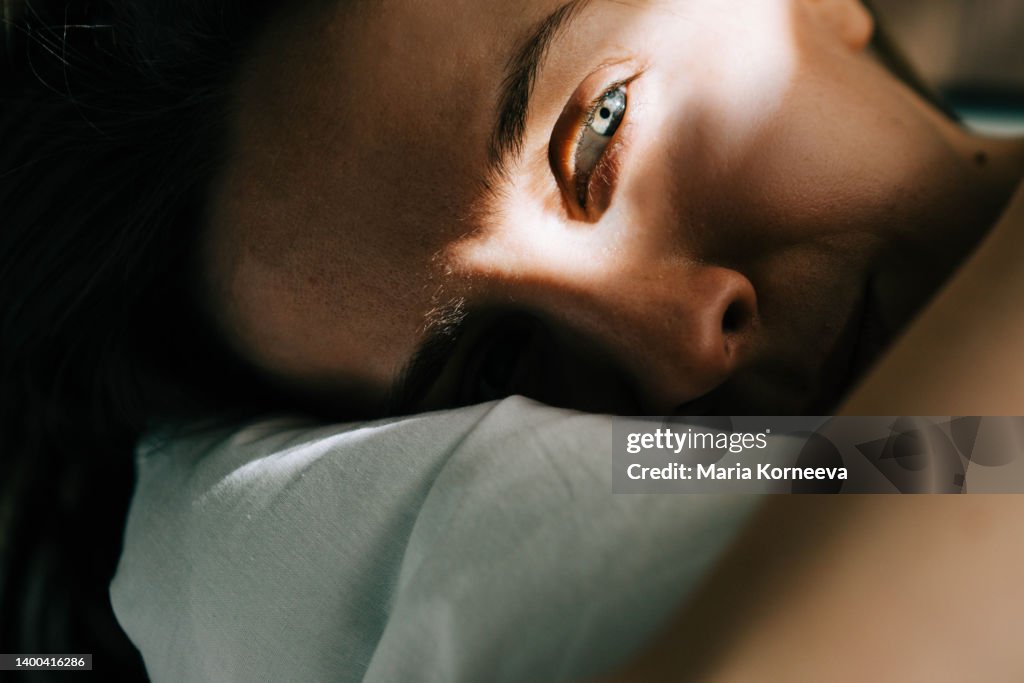 Sleepless Woman Lying In Bed Hiding Under Duvet.