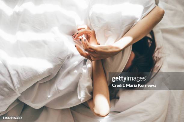 sleepless woman lying in bed hiding under duvet. - awakening stockfoto's en -beelden