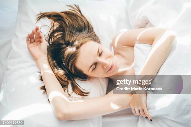 happy woman sleeping under duvet at the sunny morning, top view. - face happy sun stockfoto's en -beelden