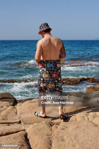 a man on a rocky beach with his back turned - toalla stock pictures, royalty-free photos & images