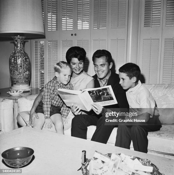 American fashion model Dusty Bartlett with her son, Steele, American actor Jeffrey Hunter and his son, Christopher, as Hunter reads from a copy of...