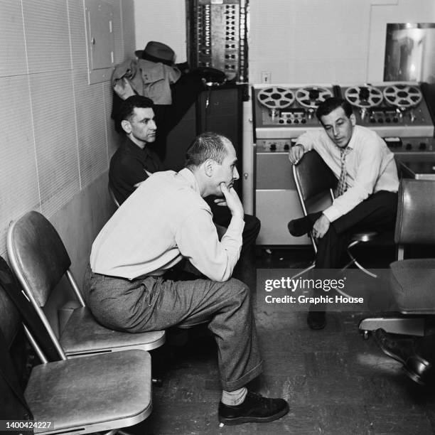 American vibraphone player Joe Roland and American clarinetist and bandleader Artie Shaw , who rests his chin in his hand as sits beside a man, at an...