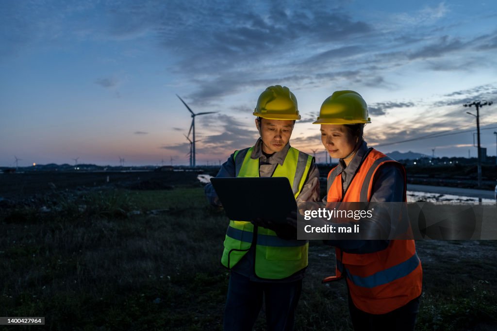 Two engineers work at a seaside wind farm