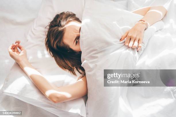 sleepless woman lying in bed. - woman pillow over head stock-fotos und bilder