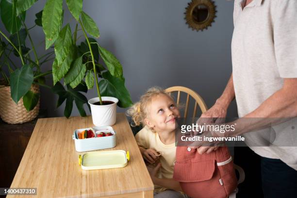 father and toddler girl packing together school lunch in backpack - school breakfast stock pictures, royalty-free photos & images