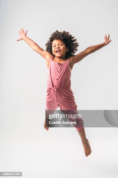 sporty black little girl jumping high - black jumpsuit stockfoto's en -beelden