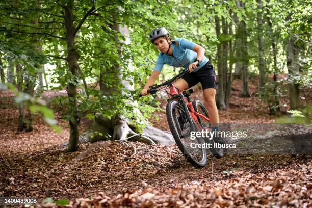 junge frau mit mountainbike auf italienischen bergen: abfahrt im wald - mountain biker stock-fotos und bilder