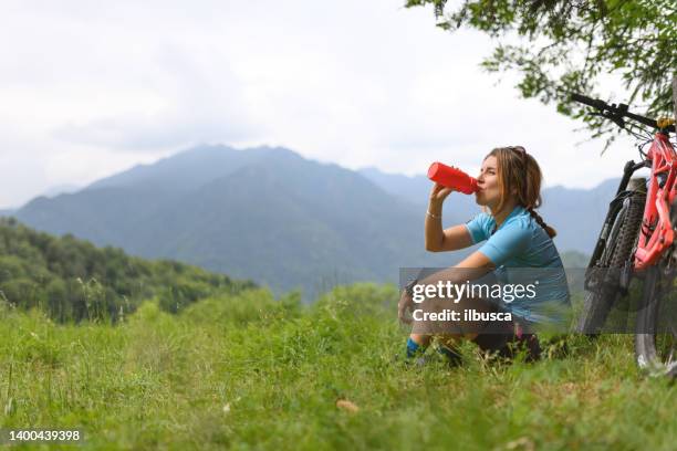 young woman with mountain bike on italian mountains: resting in the nature - 單車衫 個照片及圖片檔