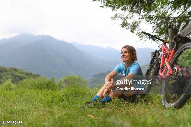 young woman with mountain bike on italian mountains: resting in the nature - 單車衫 個照片及圖片檔