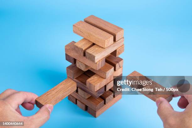 hand of man piling up and stacking a wooden block plan and strategy - jenga stockfoto's en -beelden