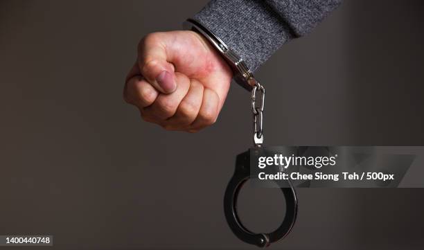 arrested mans hand with handcuffs - killer stockfoto's en -beelden