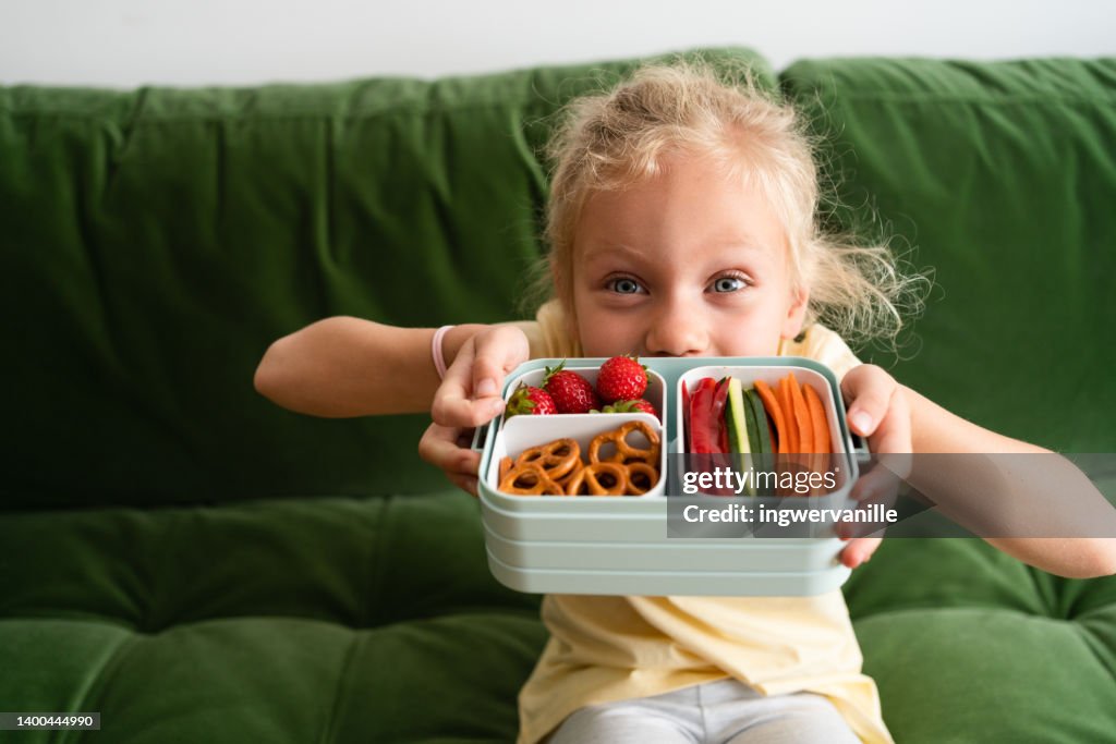 Toddler girl holding lunch box with healthy food