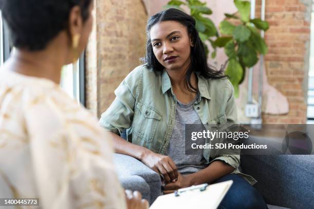 young woman focuses on female counselor's advice - psychotherapy stock pictures, royalty-free photos & images