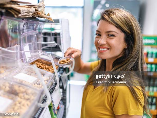 mujer comprando frutos secos en el supermercado - cashew fotografías e imágenes de stock