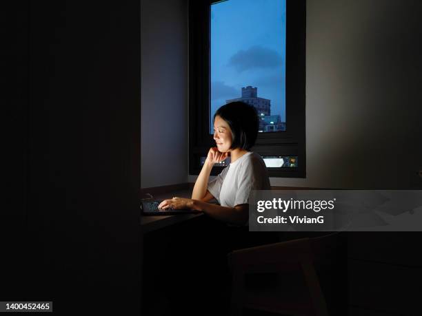 asian woman working at home with laptop at night - blackout stock pictures, royalty-free photos & images