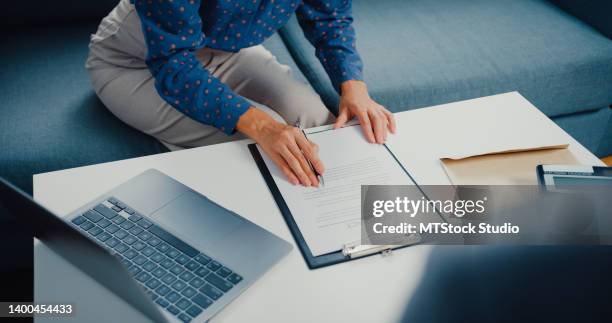 close up of asian businesswoman signing mortgage investment contract on sofa in living room at home. - bank manager imagens e fotografias de stock