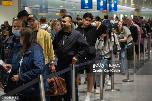 Travellers wait in a long queue to pass through the security check at Heathrow on June 1, 2022 in London, England. The aviation industry is...