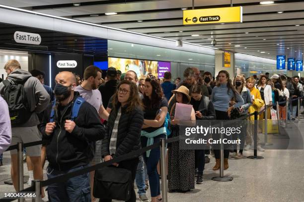 Travellers wait in a long queue to pass through the security check at Heathrow on June 1, 2022 in London, England. The aviation industry is...