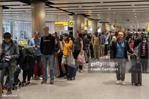 Travellers wait in a long queue to pass through the security check at Heathrow on June 1, 2022 in London, England. The aviation industry is...