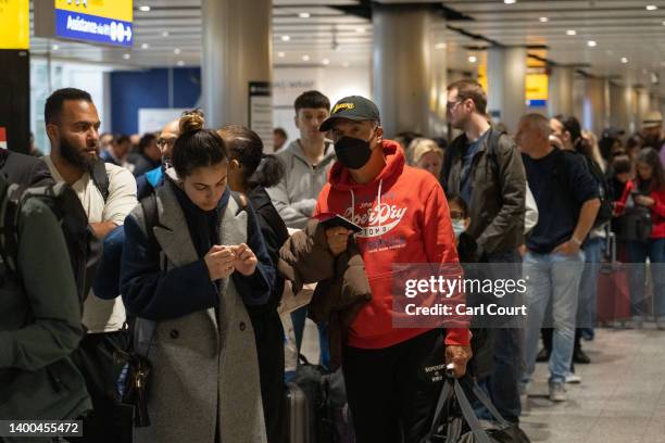 Travellers wait in a long queue to pass through the security check at Heathrow on June 1, 2022 in London, England. The aviation industry is...