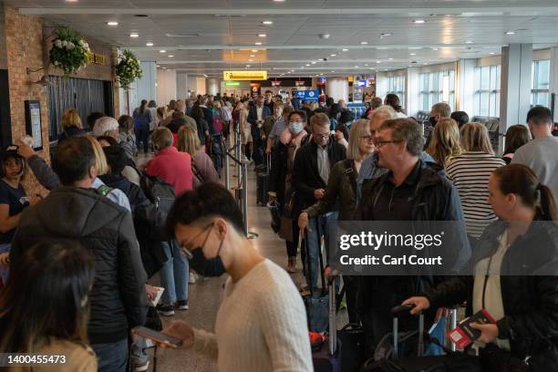 Travellers wait in a long queue to pass through the security check at Heathrow on June 1, 2022 in London, England. The aviation industry is...