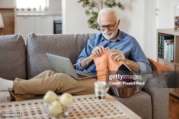 senior man learns to crochet online - man knitting stock pictures, royalty-free photos & images