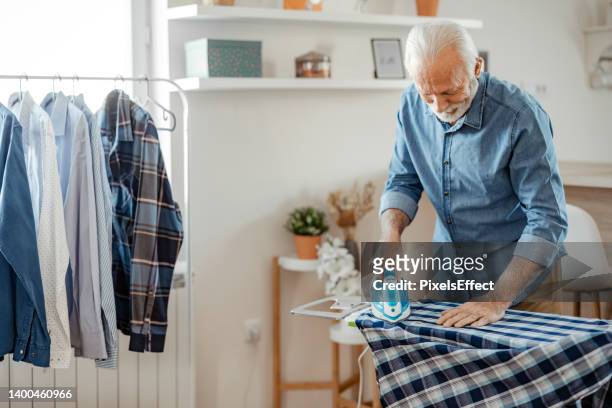 senior man at home planchando - viudo fotografías e imágenes de stock