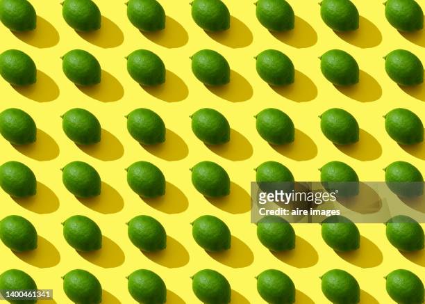 horizontal conceptual image of green lemons with hard light and shadows - hard liquor stock pictures, royalty-free photos & images