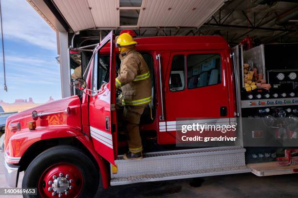 完全な防火服を着た消防署の若い消防士、投票率、消防車への乗り入れ - fire station ストックフォトと画像