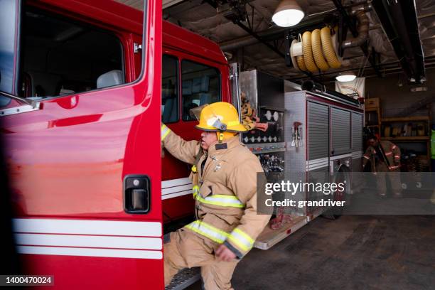 完全な防火服を着た消防署の若い消防士、投票率、消防車への乗り入れ - fire station ストックフォトと画像