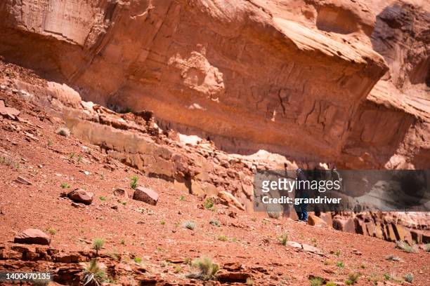 中年の先住民ナバホ族の男性、砂岩レッドロック砂漠とユタ州モニュメントバレーの断崖で一人でハイキングとウォーキング - ute ストックフォトと画像