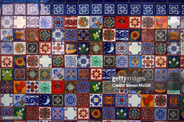 tiled wall of multi-colored, clashing mexican-themed patterned tiles - abundance tiles stock pictures, royalty-free photos & images