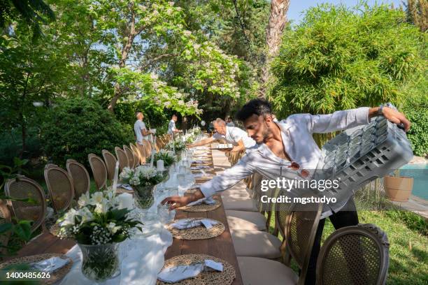 waiters setting banquet tables for wedding dinner in the backyard of the house - wedding table setting imagens e fotografias de stock