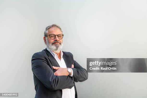 confident senior businessman standing with arms crossed against gray background. - portrait white hair studio stock pictures, royalty-free photos & images