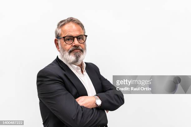 portrait of senior businessman standing with arms crossed against white background. - ceo white background stock pictures, royalty-free photos & images