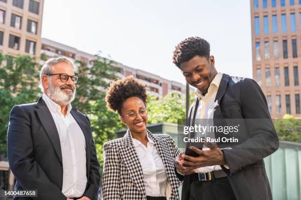 young businessman sharing smartphone with colleagues in city street - pensioners demonstrate in barcelona stock pictures, royalty-free photos & images