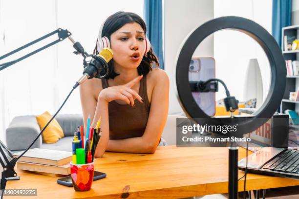 adolescente faisant les réglages du téléphone et enregistrant un podcast. jeune femme travaillant au studio de diffusion fait maison - blog photos et images de collection