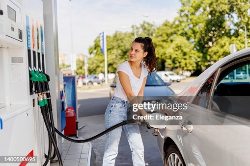 Mujer molesta reabasteciendo el tanque de gasolina en la bomba de combustible Mujer molesta reabasteciendo el tanque de gasolina en la bomba de combustible